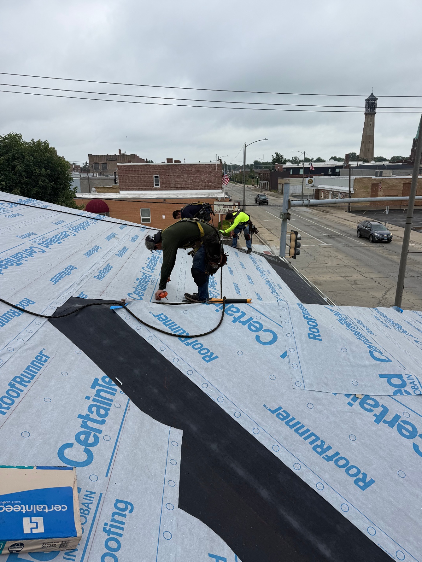 Rico's Contracting crew installing roof underlayment above a downtown street